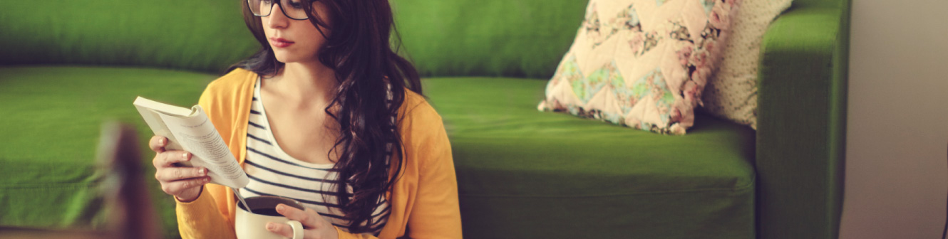 Woman reading a book by a couch