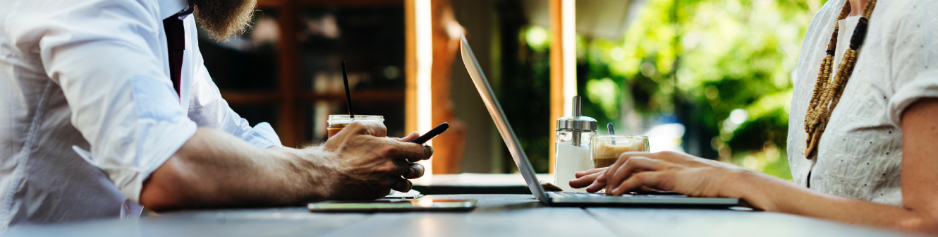 Couple sitting together on laptop and phone