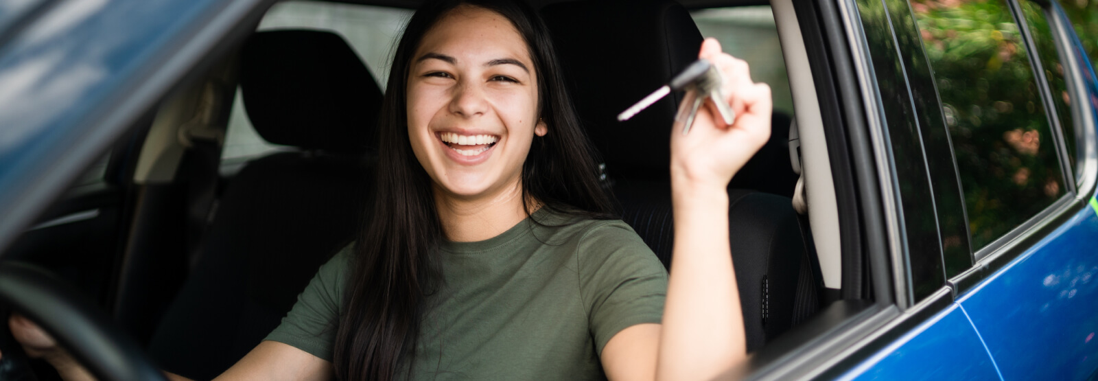 A young woman sitting in a car and holding the keys