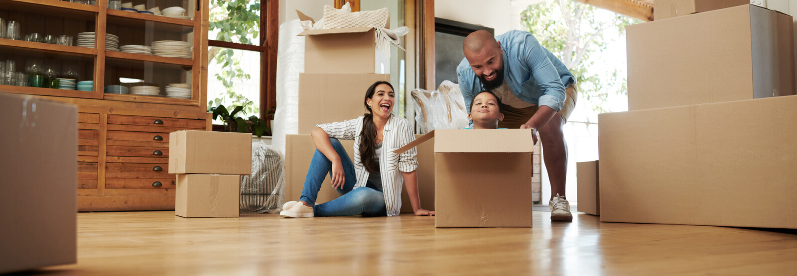 A young family playing with moving boxes