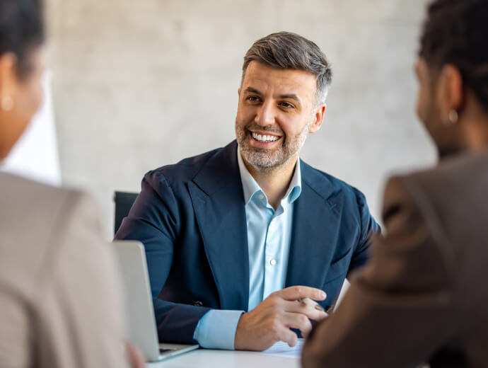 A businessman looking and smiling at someone slightly out of frame